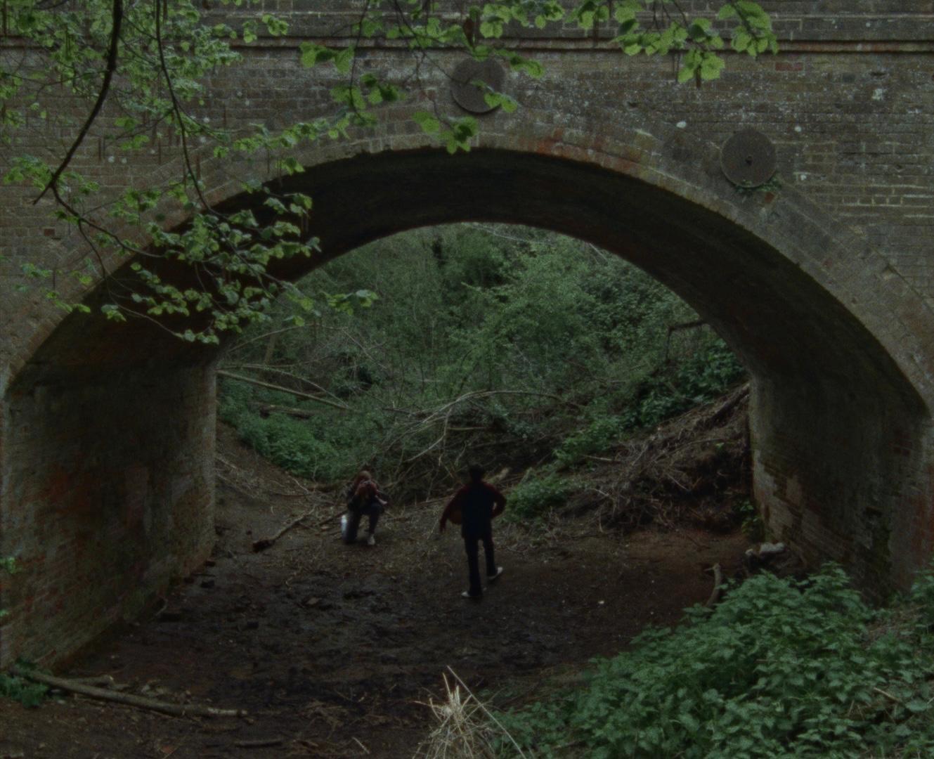 Two figures beneath a brick bridge
