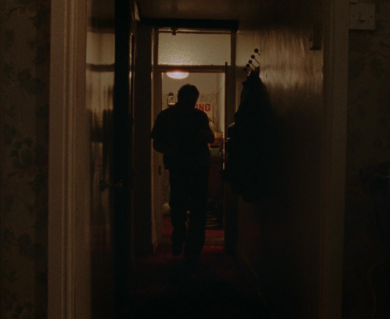 A figure walking through a dim hallway