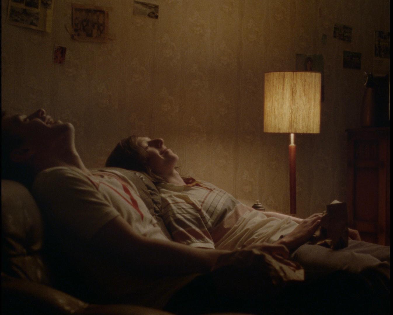 Two people lying back in a dimly lit room