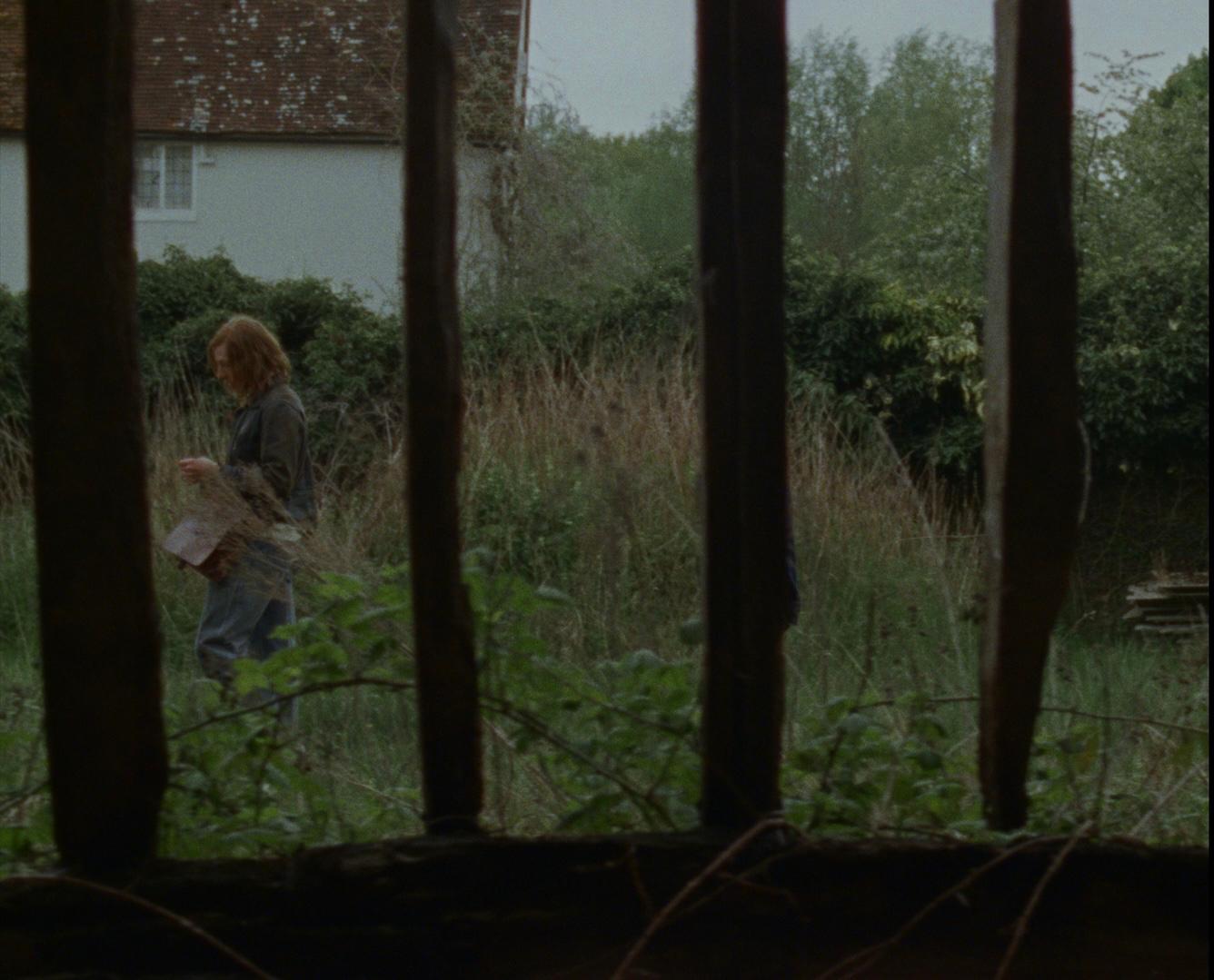A figure seen through the broken frame of a window